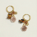 Pendientes de aro dorados con charms de rosa tallada y cuentas en tonos tierra sobre fondo blanco.