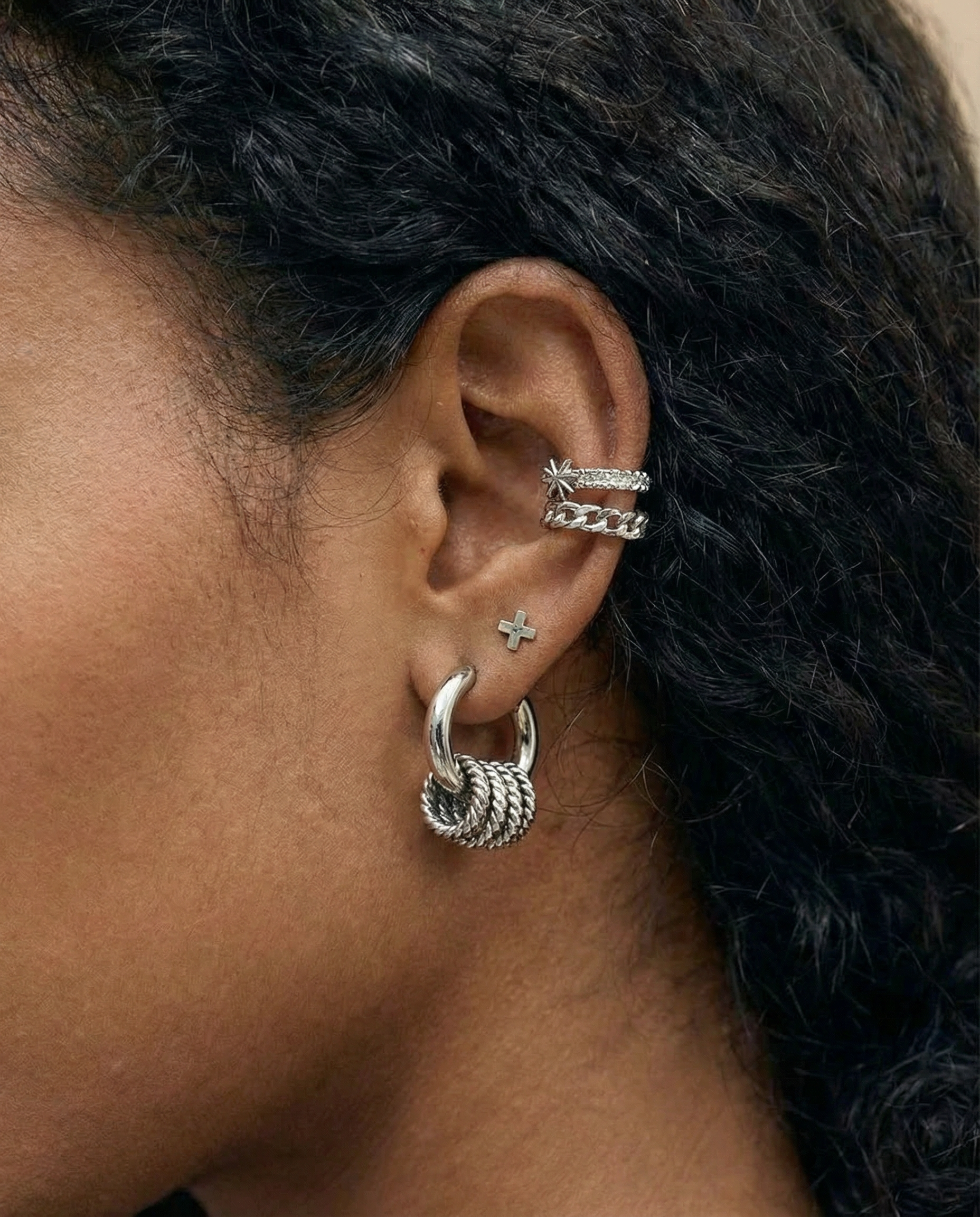 Detalle de pendiente plateado con nudo en acero inoxidable en la oreja, vista lateral.