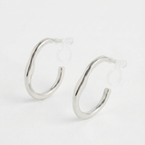 Detalle de pendientes plateados ondulados con sistema de clip en acero inoxidable.