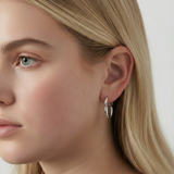 Pendientes plateados de aro ondulado con cierre de clip en la oreja de una modelo rubia, vista lateral.