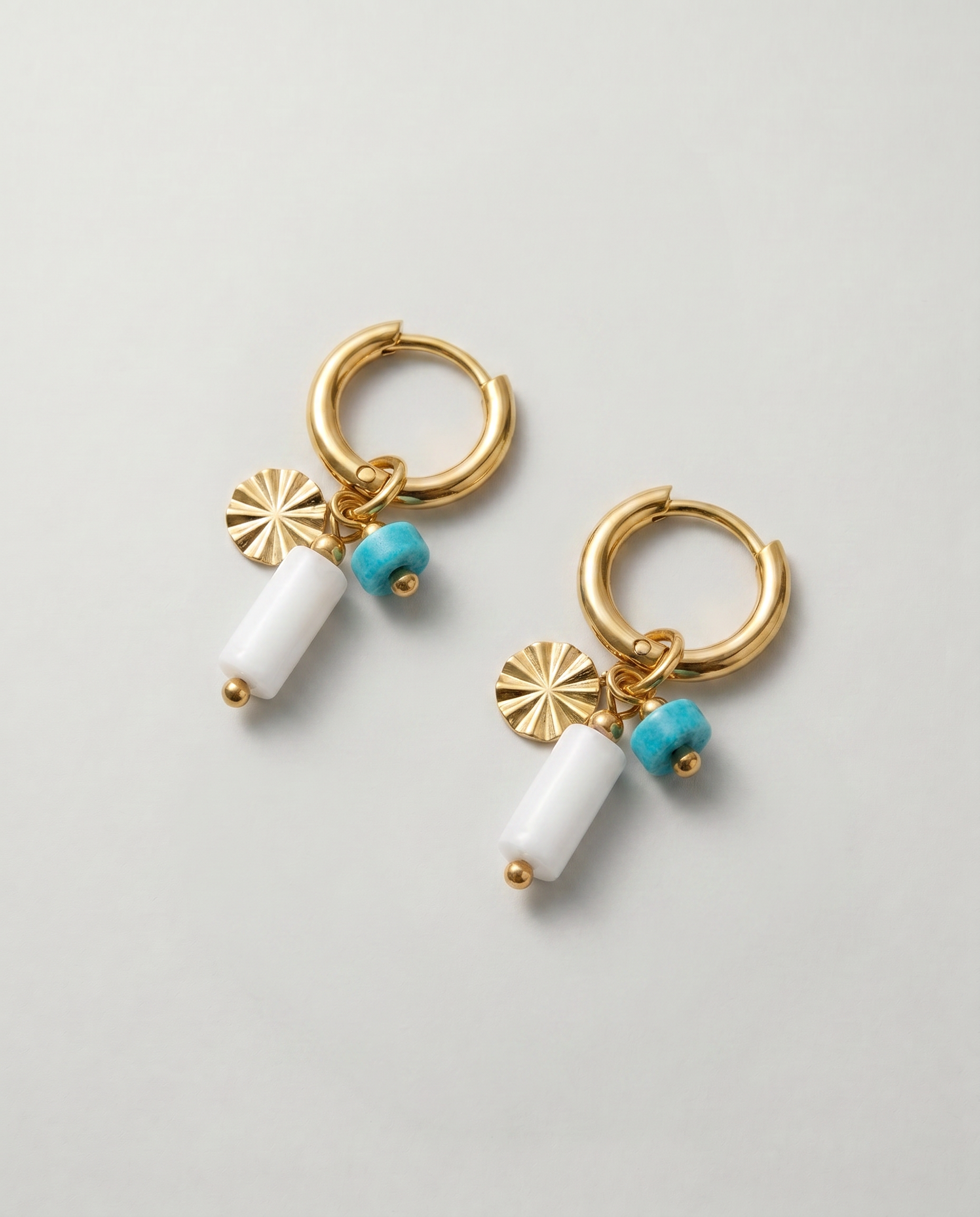 Pendientes de aro dorados con piedra blanca y detalle de piedra turquesa.