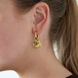 Mujer con pendientes de aro dorado con charm de cangrejo y abalorios

