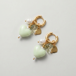 Pendientes de acero inoxidable con corazón de cerámica verde, perla y cristal sobre fondo blanco.