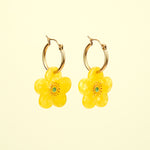 Pendientes florales amarillos de Coucou Suzette fotografiados sobre fondo amarillo.