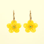 Pendientes de Coucou Suzette en forma de flor amarilla con pistilo verde, vista frontal sobre fondo claro.