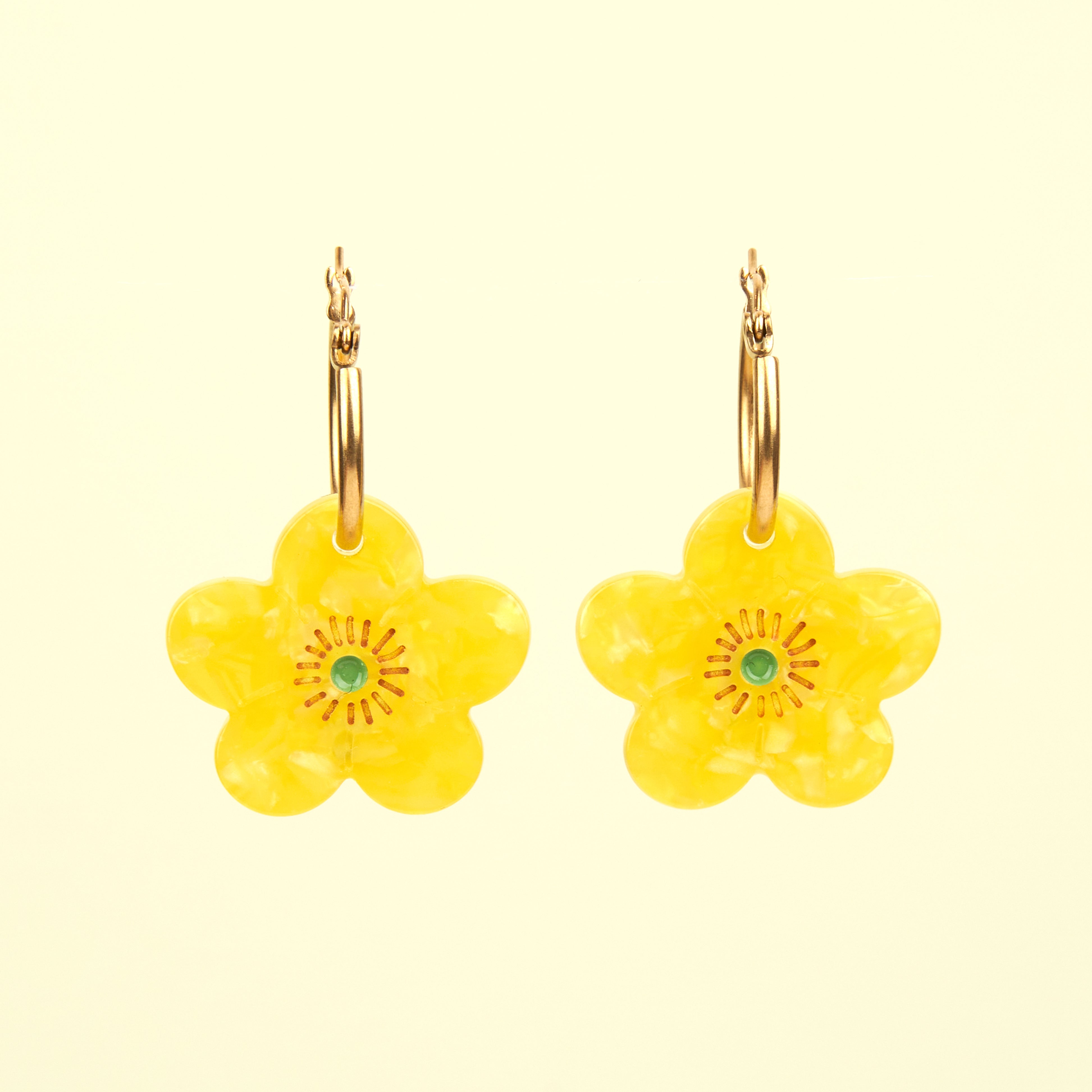 Pendientes de Coucou Suzette en forma de flor amarilla con pistilo verde, vista frontal sobre fondo claro.