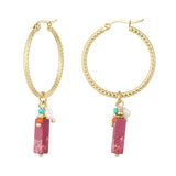 Detalle de pendiente dorado con piedra rosa, cuentas de vidrio y perla blanca.


