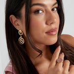 Mujer con pendientes dorados largos en forma de espiral, estilo retro.