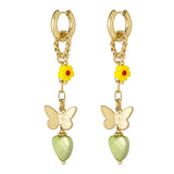 Pendientes dorados con charms de mariposa, flor amarilla y corazón verde, vista frontal sobre fondo blanco.