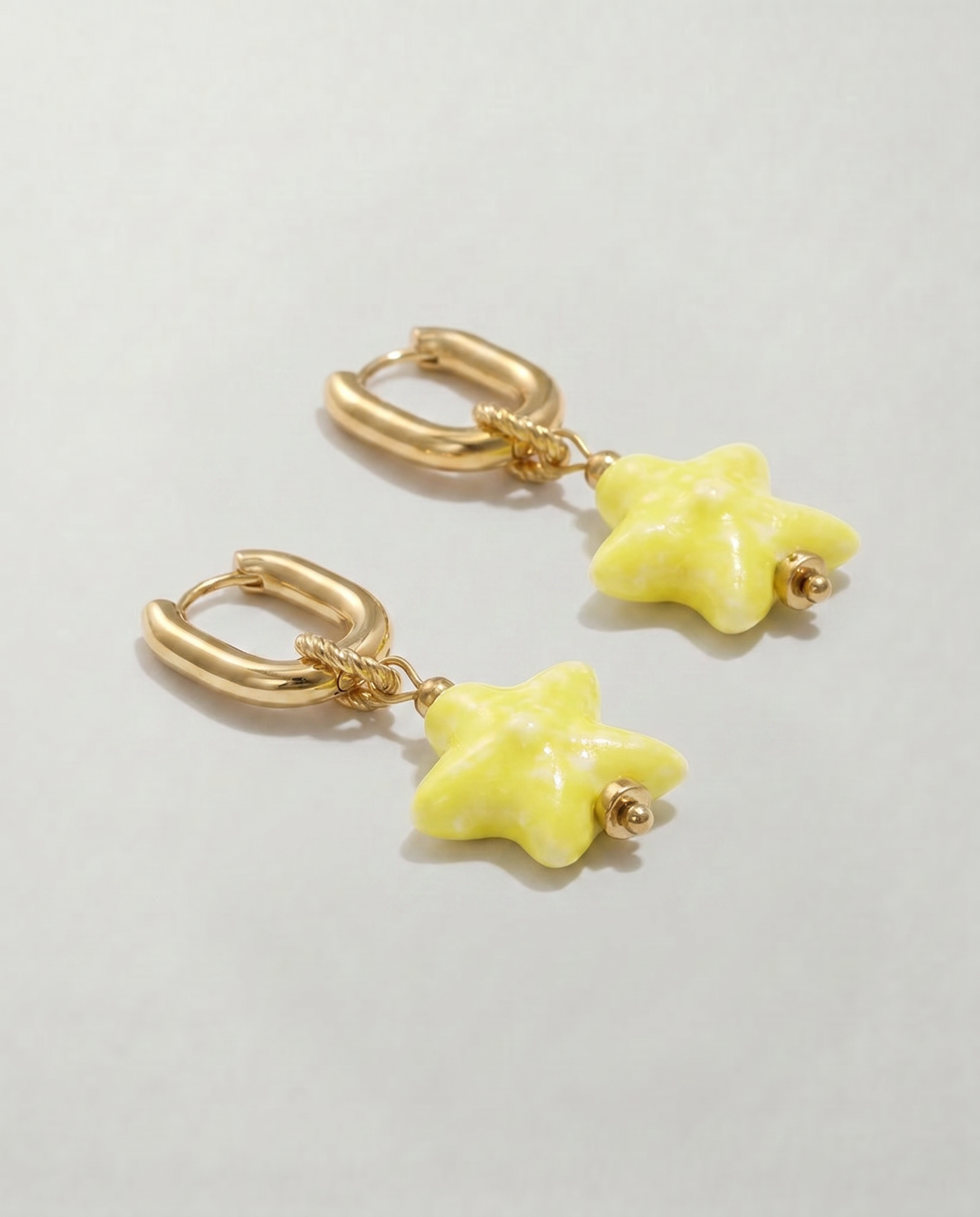 Pendientes de acero inoxidable con aro y estrella amarilla de cerámica.