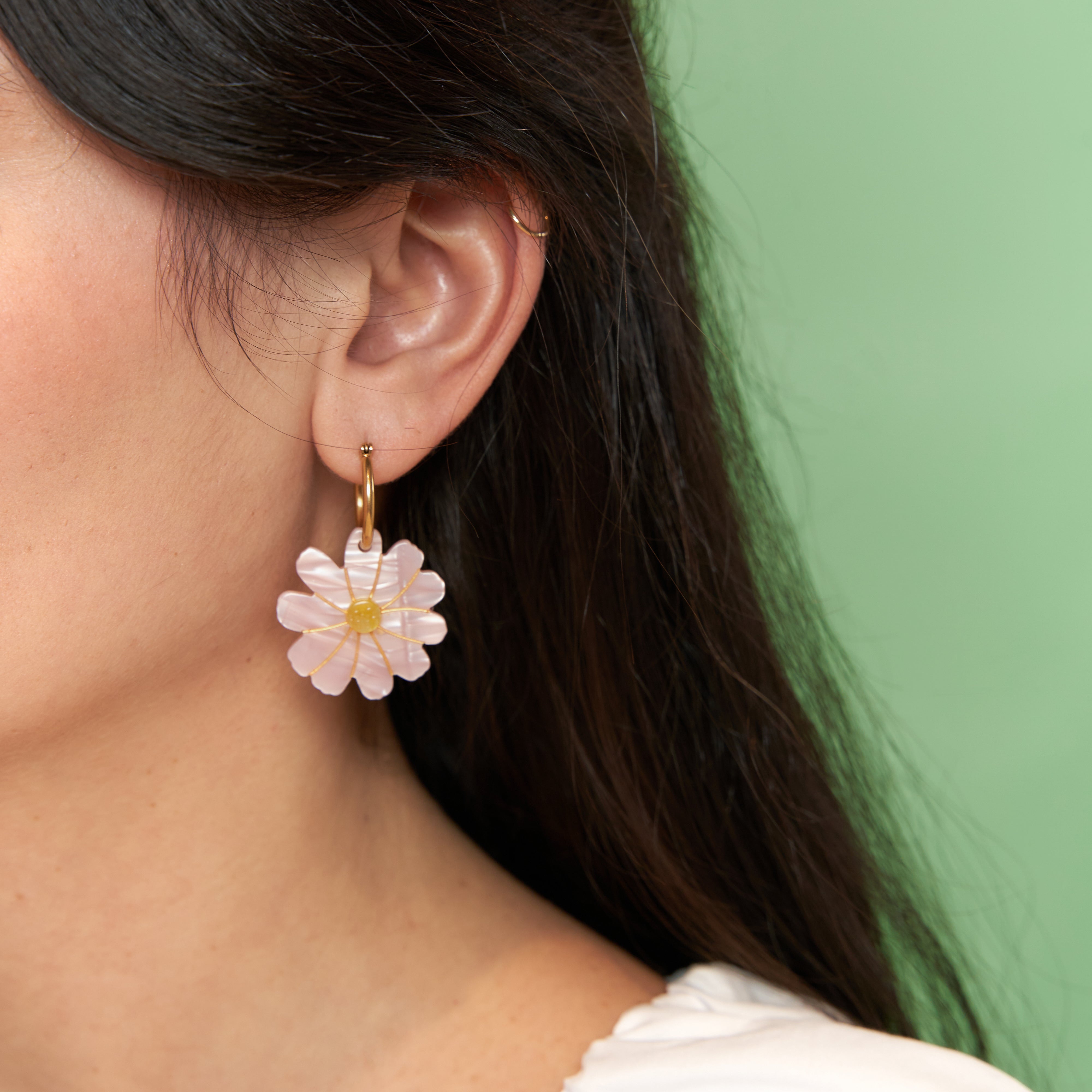 Mujer con pendientes flor rosa Coucou Suzette colocados en un recogido alto.

