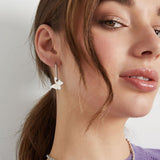 Primer plano de pendiente plateado con charm de mariposa.