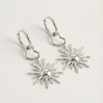 Detalle de pendientes plateados con sol estilizado y aro con corazón.