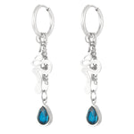 Pendientes plateados con charm de serpiente y piedra azul en forma de lágrima, vista frontal.

