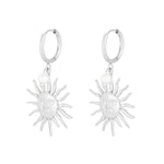 Pendientes plateados con charm de sol y perla, vista frontal sobre fondo blanco.