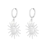 Pendientes plateados con charm de sol y perla, vista frontal sobre fondo blanco.