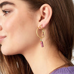 Detalle de pendiente dorado con piedra rosa, cuentas de vidrio y perla blanca.