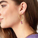Detalle de pendiente dorado con piedra rosa, cuentas de vidrio y perla blanca.