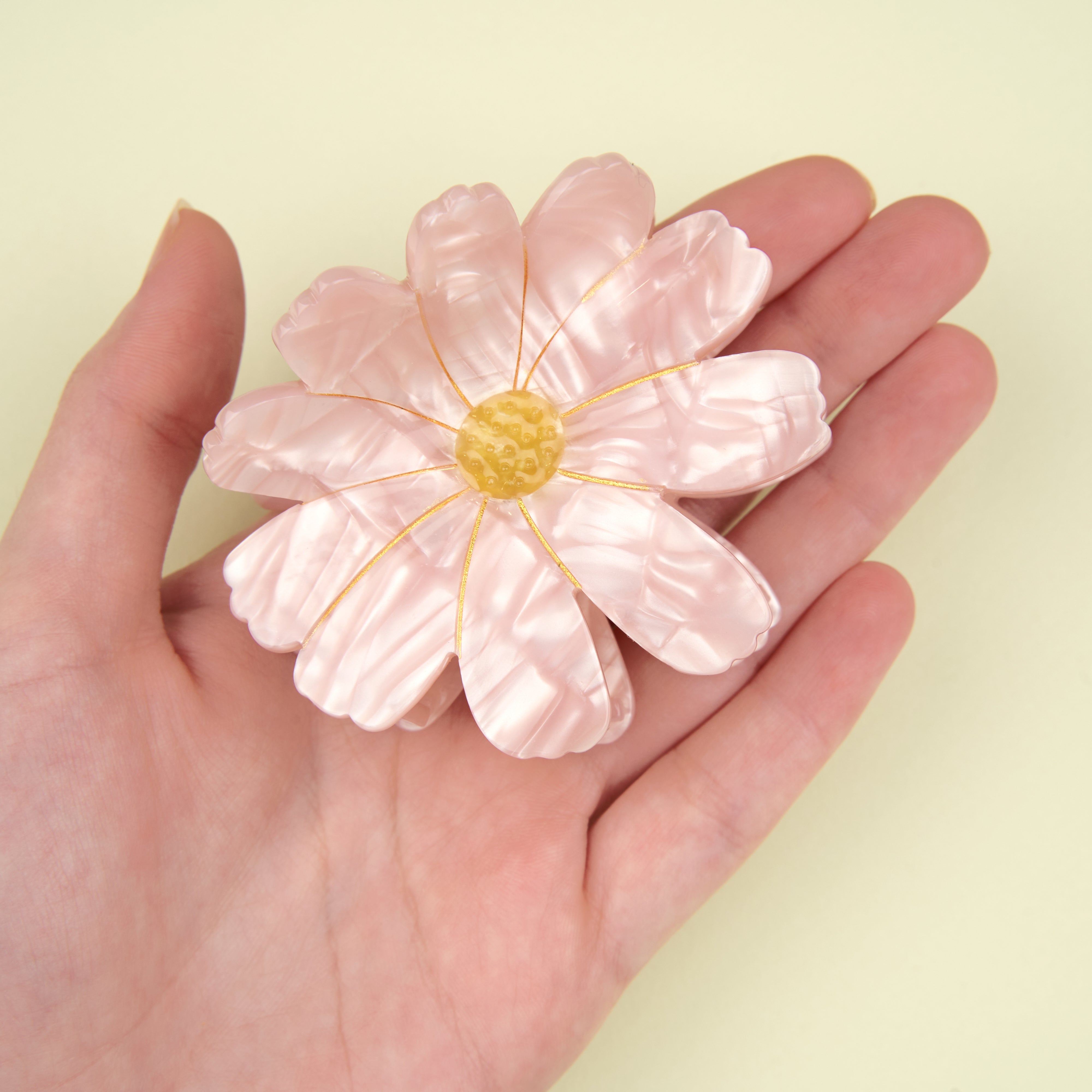 Detalle de la pinza Coucou Suzette en forma de flor rosa con centro amarillo.

