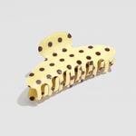 Pinza para el pelo efecto acetato amarilla con estampado de lunares marrones.