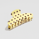 Pinza para el pelo efecto acetato amarilla con estampado de lunares marrones.