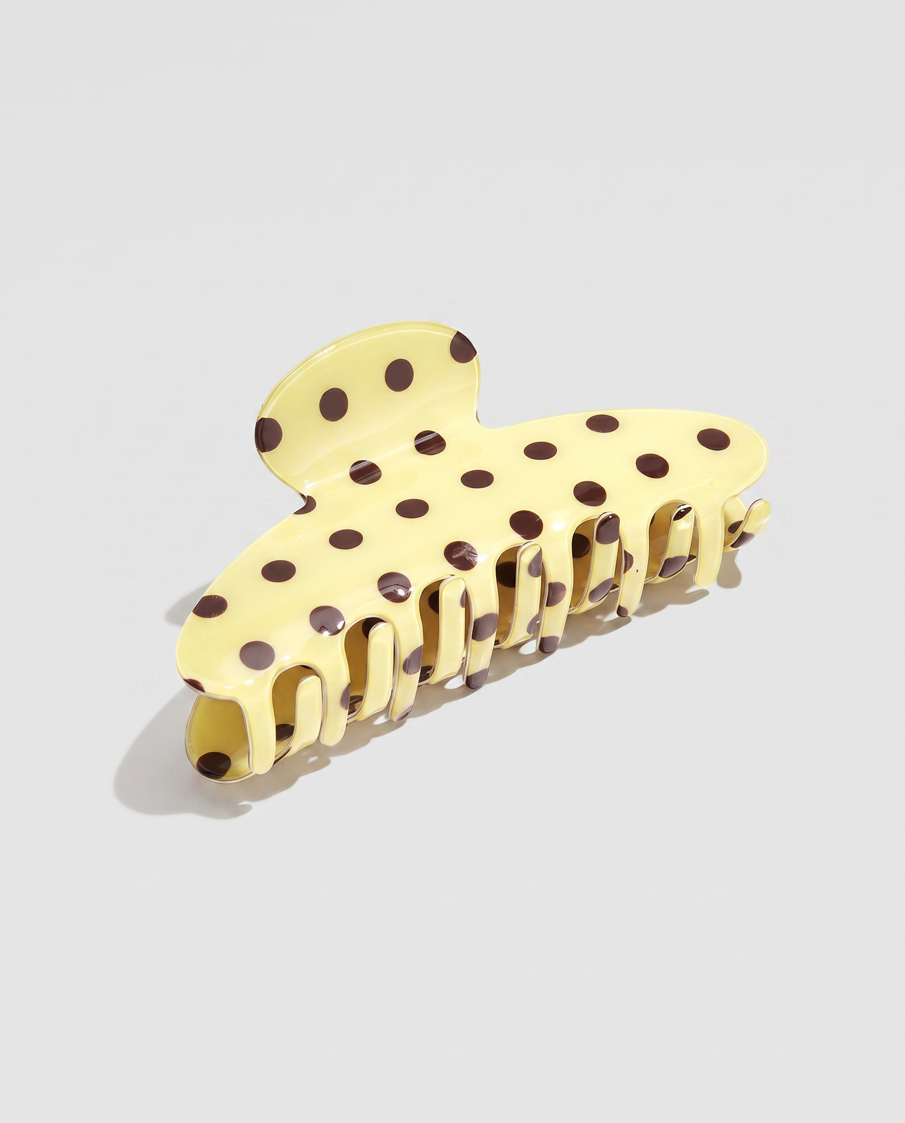 Pinza para el pelo efecto acetato amarilla con estampado de lunares marrones.