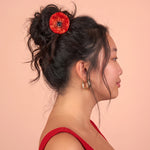 Pinza de pelo con forma de flor roja colocada en un moño.