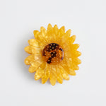 Pinza de pelo de acetato con forma de girasol amarillo y centro marrón.