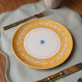 Plato de cerámica amarillo con borde floral y detalle central en azul.