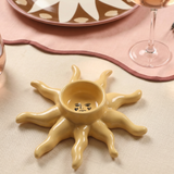 Detalle del portavelas de cerámica amarillo con diseño de sol.