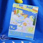  Caja del Puzzle Tarta de Limón con diseño minimalista y letras en amarillo y azul.