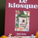 Caja burdeos del puzzle Le Kiosque de 1000 piezas de Jour Férié, con ilustración de un quiosco parisino.