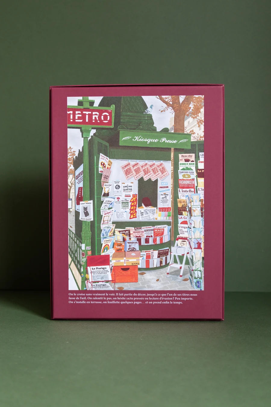 Parte trasera de la caja burdeos del puzzle Le Kiosque, con ilustración completa y texto descriptivo en francés.