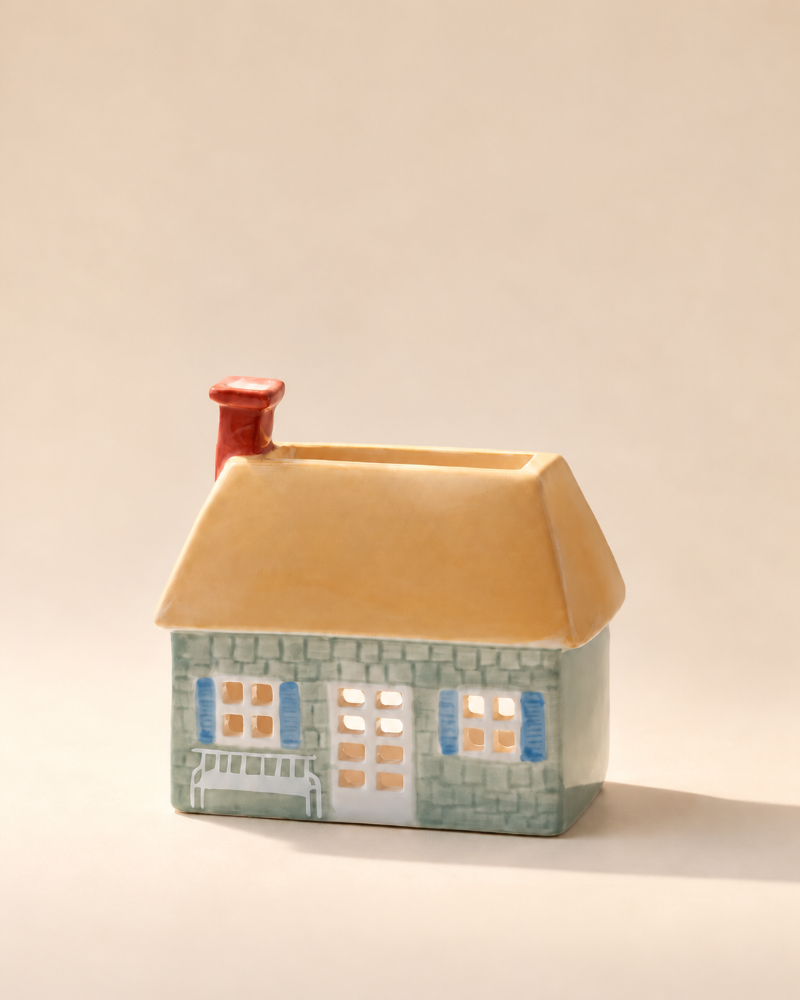 Quemador de incienso PADDYWAX en forma de casa verde con ventanas azules, tejado crema y chimenea roja.