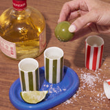 Set de tequila de cerámica con dos vasos verdes sobre bandeja azul, lima y sal, junto a una botella de tequila.