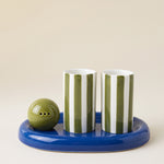 Set de tequila Lily de Here's How con dos vasos de rayas verdes y blancas, salero verde y bandeja azul de cerámica.
