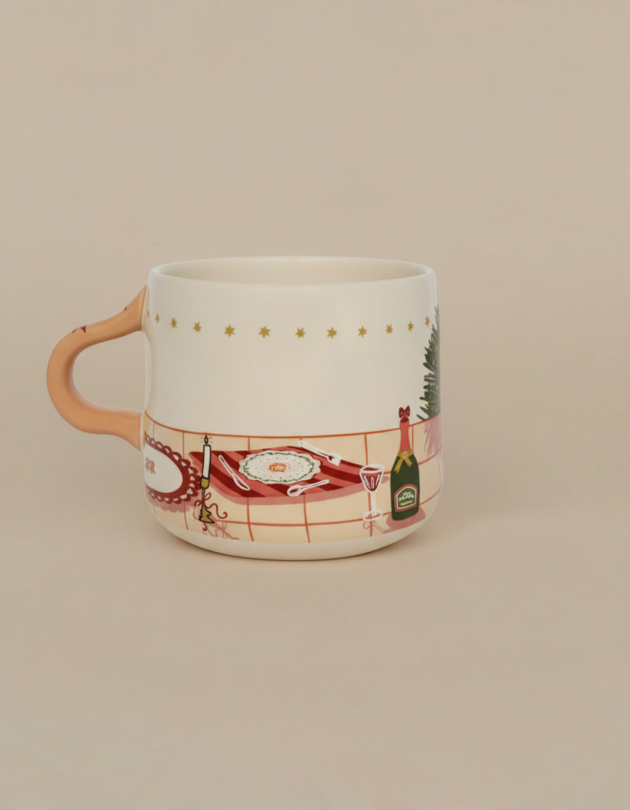 Taza de cerámica ilustrada en tonos rojos y dorados con mesa navideña, vista lateral.