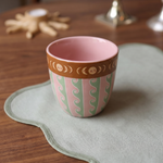 Taza de cerámica rosa sobre una mesa con decoración.