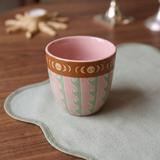 Taza de cerámica rosa sobre una mesa con decoración.