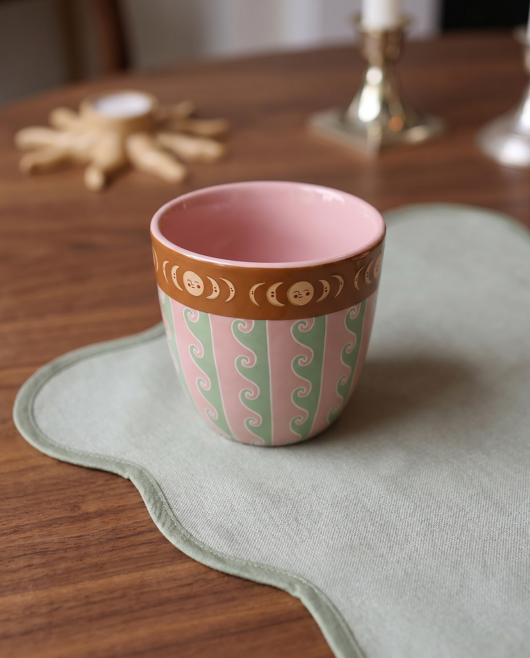 Taza de cerámica rosa sobre una mesa con decoración.