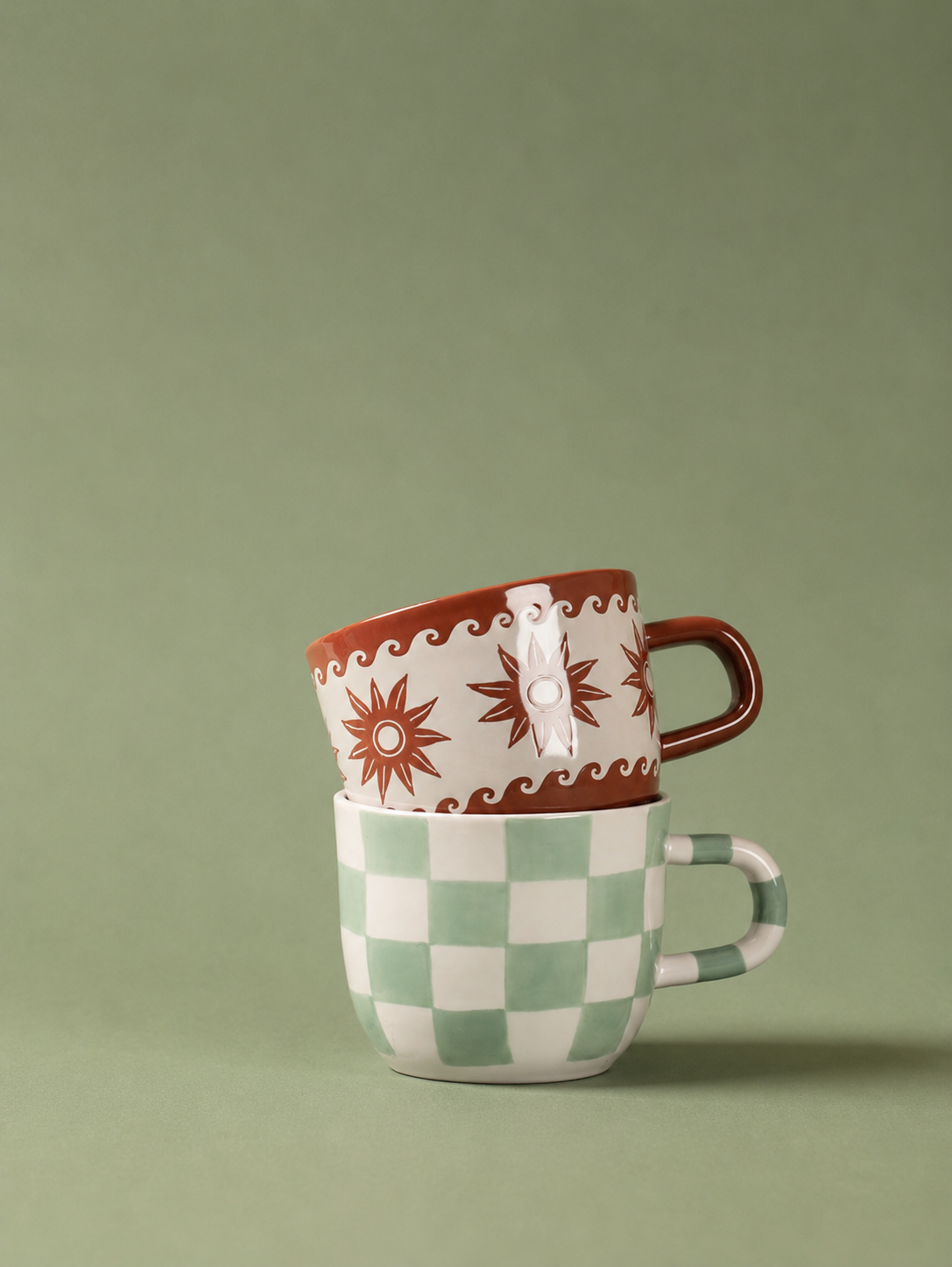Taza marrón Estrellas y Olas apilada sobre otra taza de cerámica.