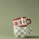 Taza marrón Estrellas y Olas apilada sobre otra taza de cerámica.