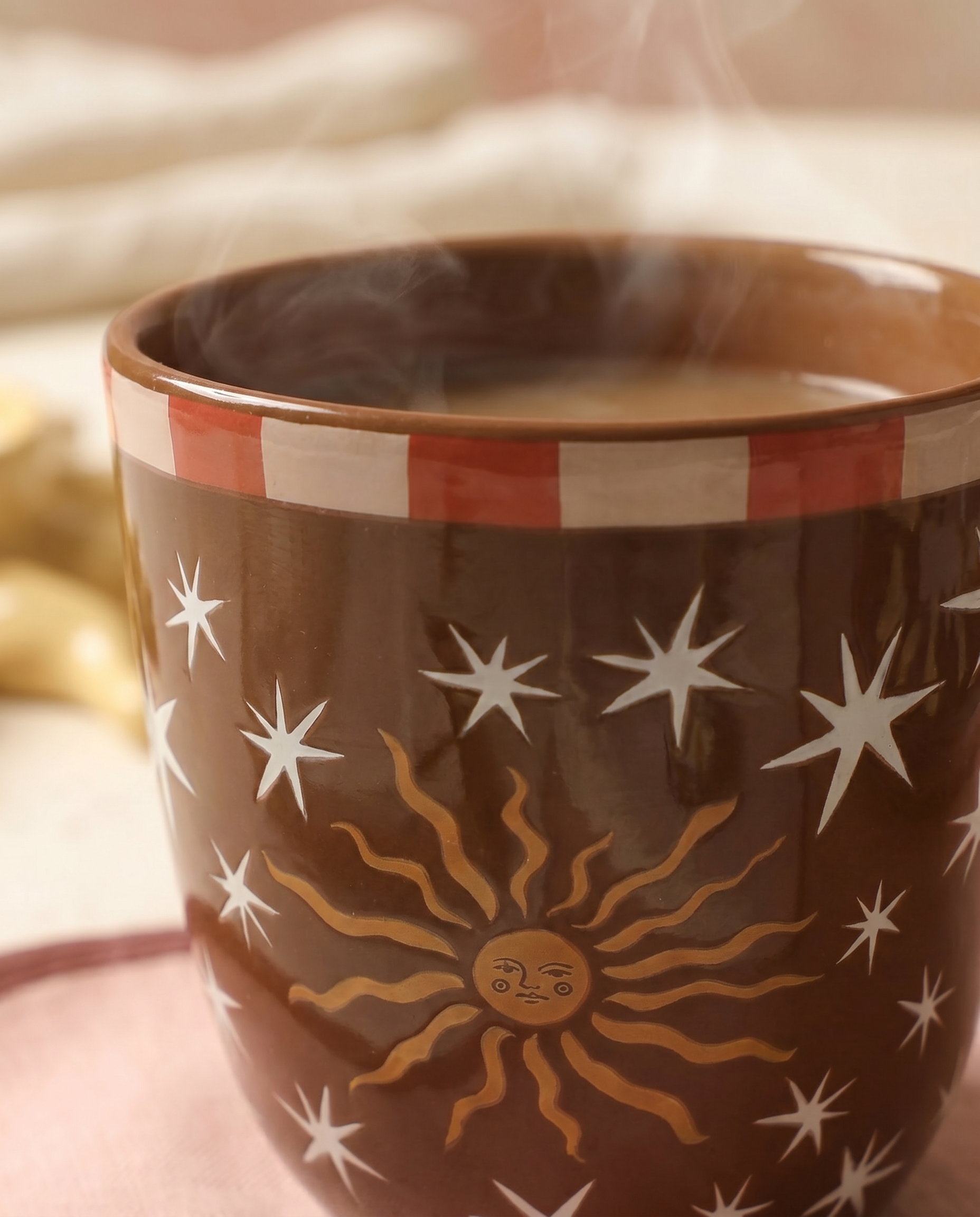 Detalle del estampado de sol y estrellas de la taza de cerámica marrón.