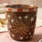 Vista frontal de la taza marrón Sol y Estrellas con café caliente.