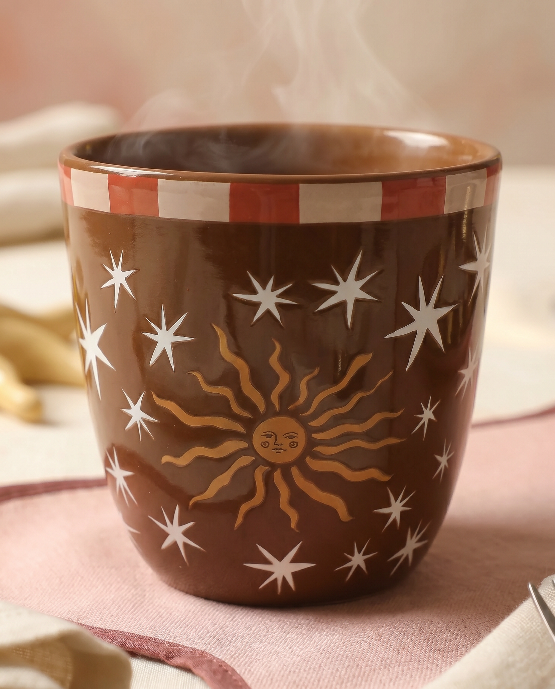 Vista frontal de la taza marrón Sol y Estrellas con café caliente.