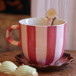 Taza de cerámica con rayas rosas y blancas sobre una mesa de madera.