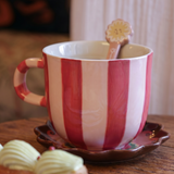 Taza de cerámica con rayas rosas y blancas sobre una mesa de madera.