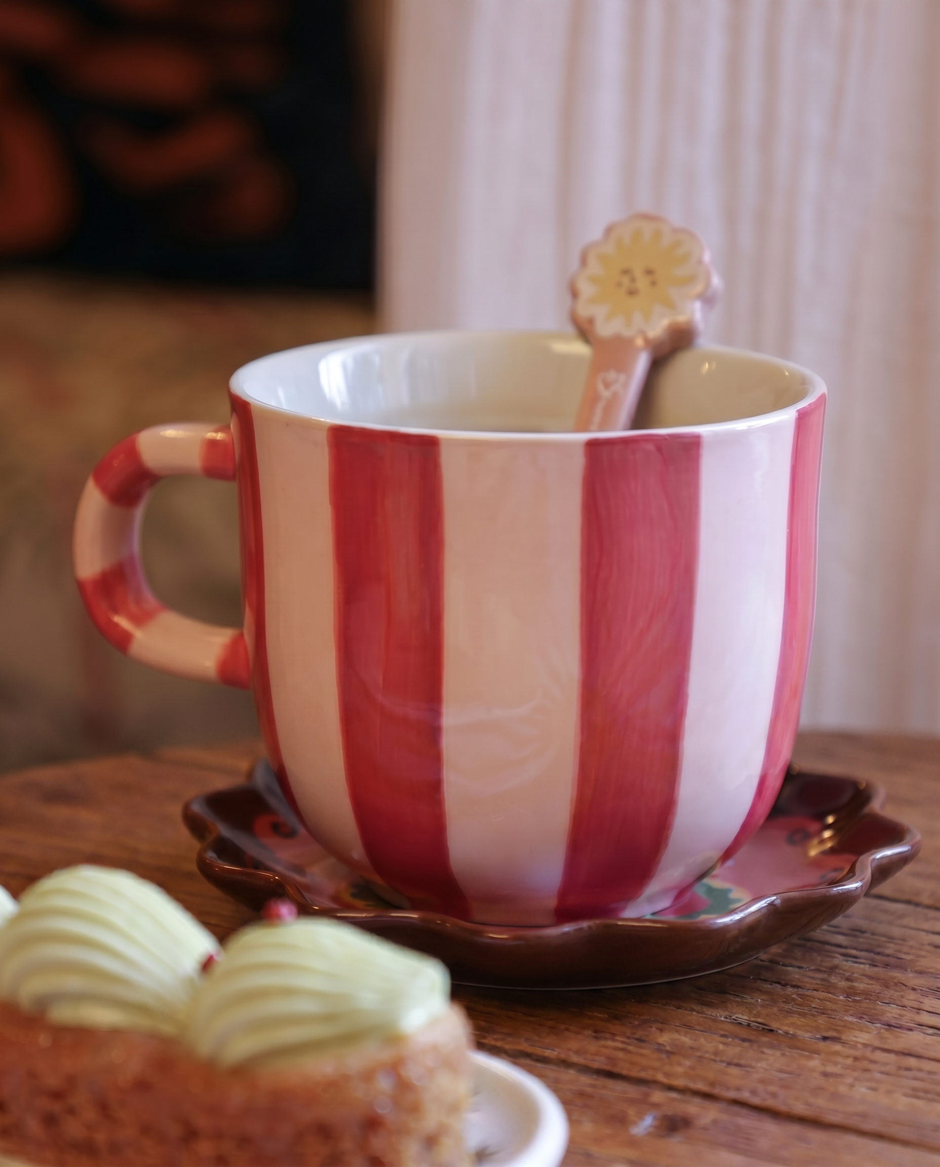 Taza de cerámica con rayas rosas y blancas sobre una mesa de madera.