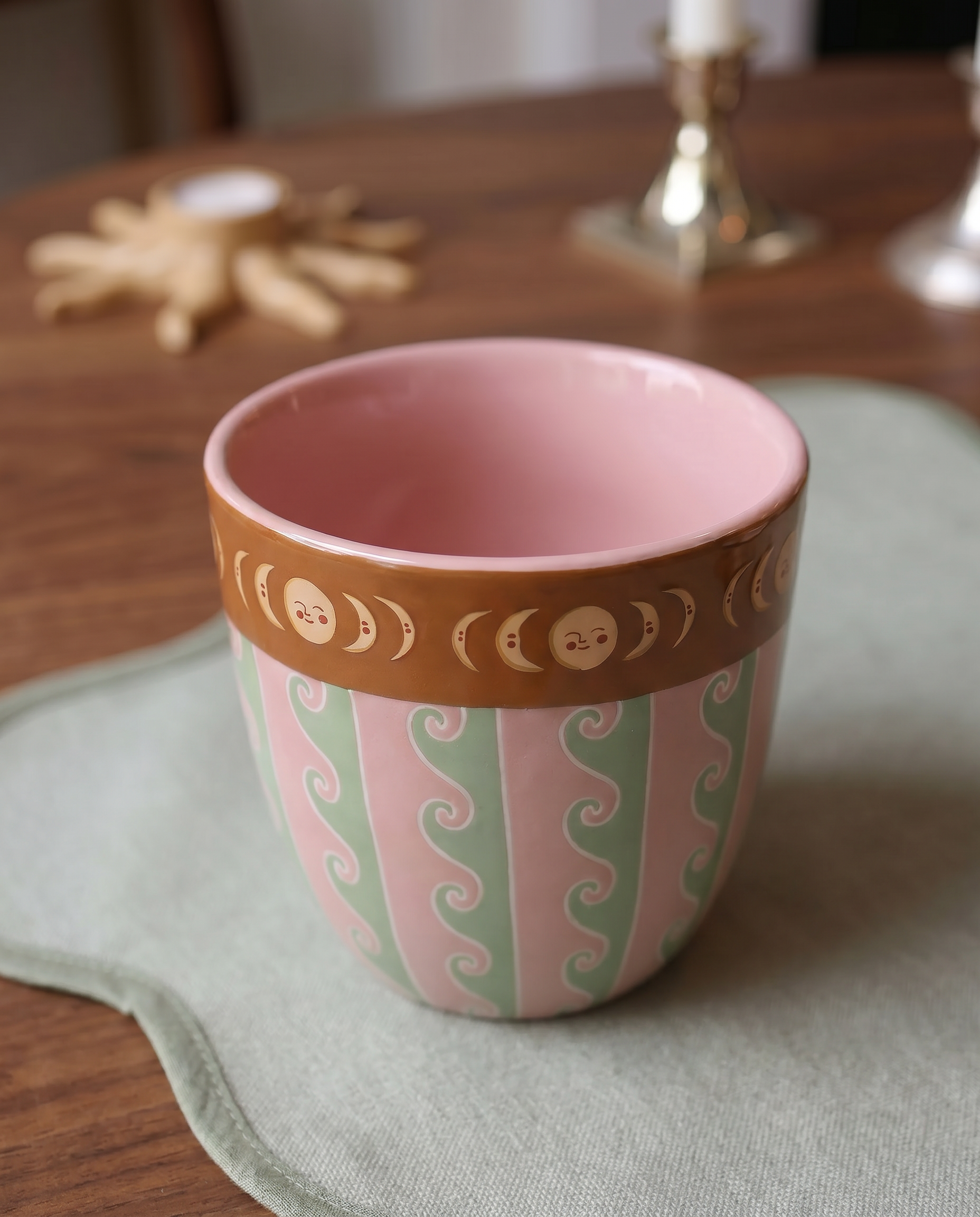 Taza de cerámica rosa con estampado de ondas y borde decorado con lunas.