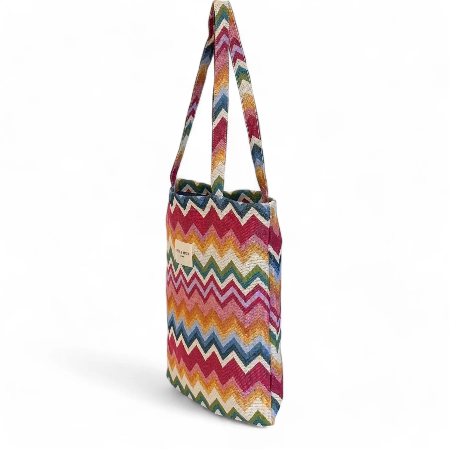 Tote bag colorida colgada, con patrón de zigzag y etiqueta De La Mur